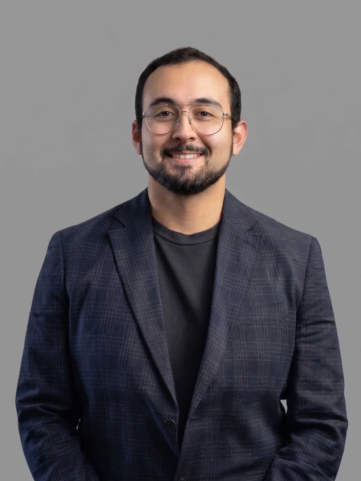 Retrato profesional de estudio de Benjamín Brante sonriendo, con blazer azul marino y lentes, proyectando cercanía y confianza para su portafolio profesional.